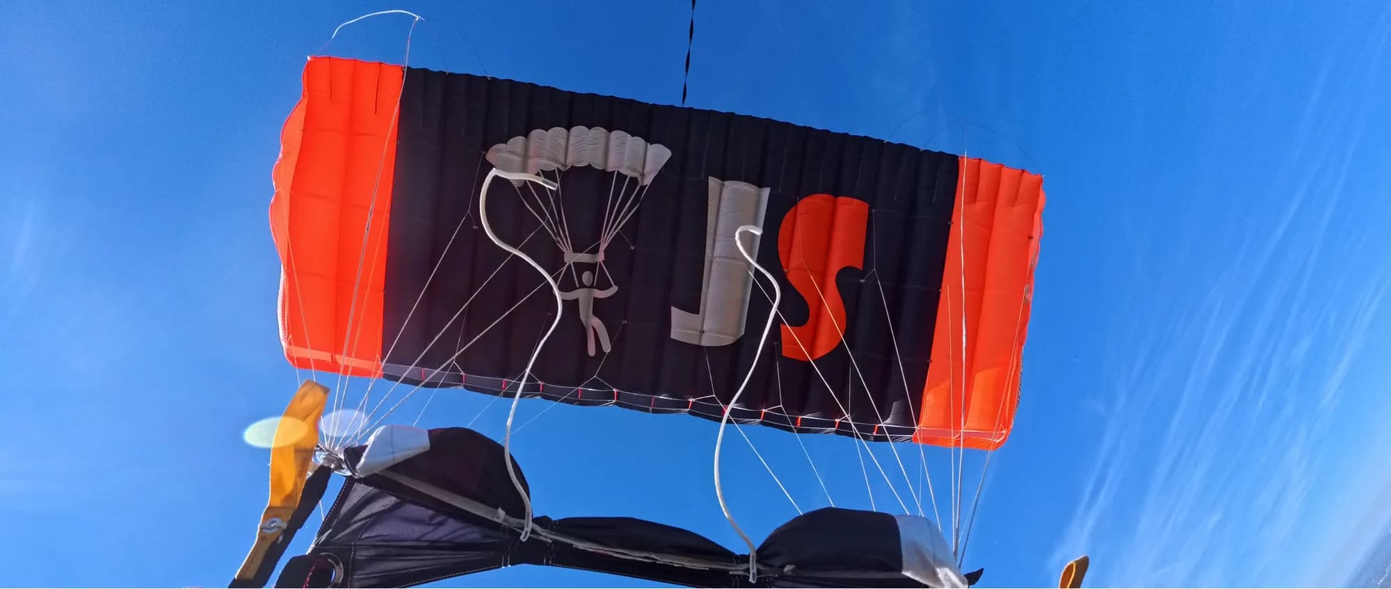 Jump Slut branded parachute canopy overhead in flight, shot from the harness
